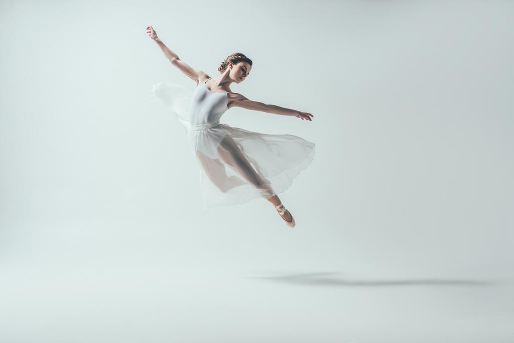 白いドレスが白で隔離のスタジオでジャンプのエレガントなバレエ ダンサー ロイヤリティフリー写真 画像素材