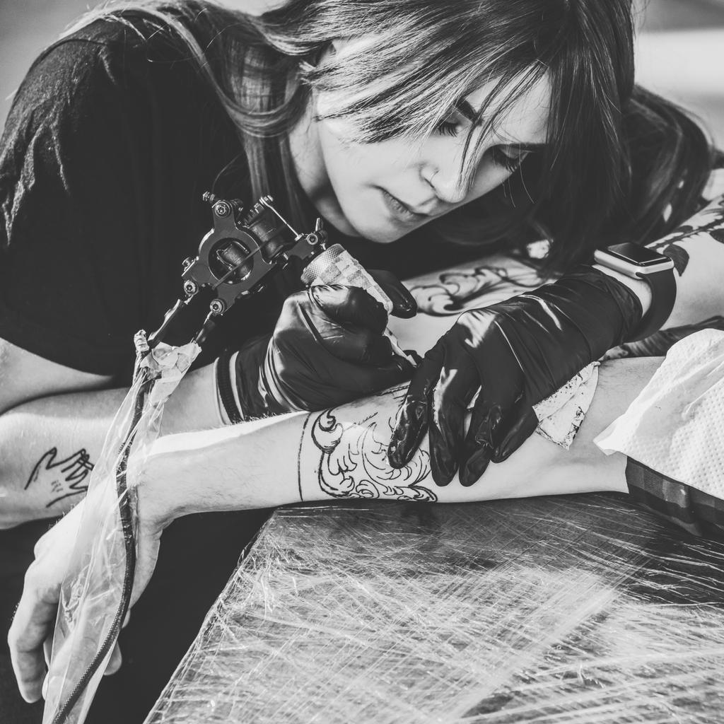 手袋腕部分タトゥー スタジオでの作業に集中している女性アーティストの黒と白の写真 ロイヤリティフリー写真 画像素材