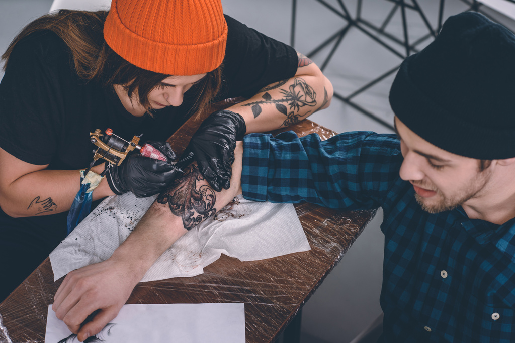 若い男性と女性タトゥー スタジオ タトゥー処理中にマスター ロイヤリティフリー写真 画像素材