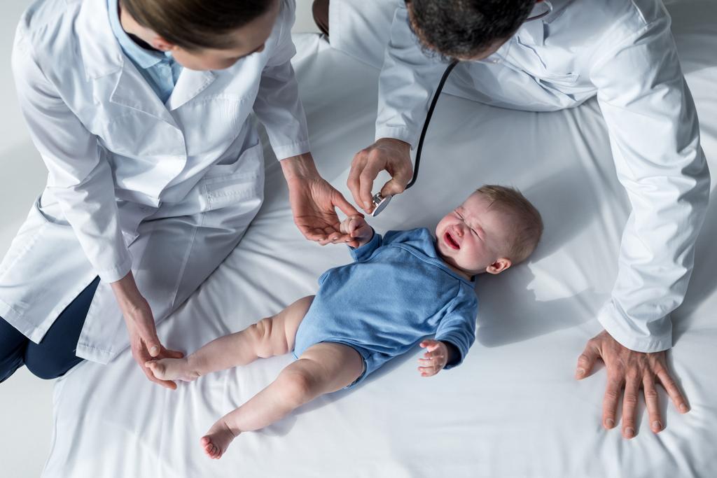 泣いている赤ちゃんの息をチェックしようと小児科医のハイアングル ロイヤリティフリー写真・画像素材