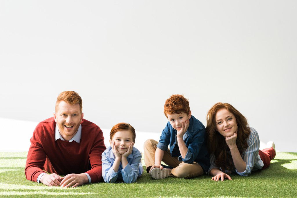 2 人の子供を草の上に横たわる グレーのカメラで笑顔赤毛の幸せ家族 ロイヤリティフリー写真 画像素材