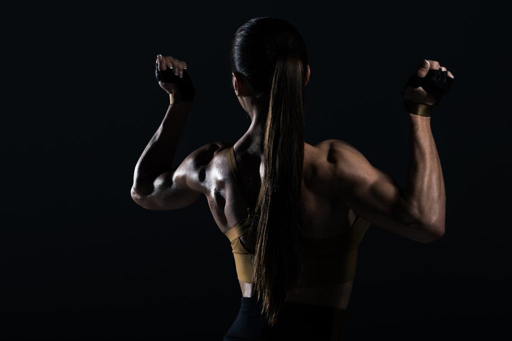ポーズと筋肉 黒に分離を示す強いメスのボディービルダーの背面図 ロイヤリティフリー写真 画像素材