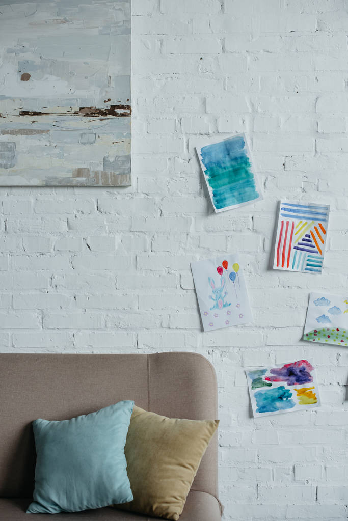 ソファと白いレンガの壁にカラフルな絵と空の幼稚な部屋のクローズ アップ表示 ロイヤリティフリー写真 画像素材