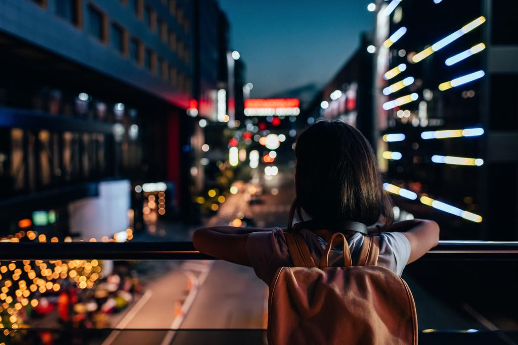 バックパック路上に立って 夜の街の灯を見ていると女性の背面図 ロイヤリティフリー写真 画像素材