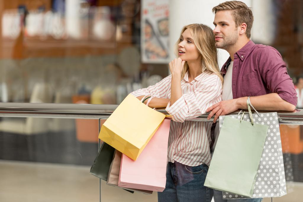 買い物客のカップルを浮かべて紙袋ショッピング モールに立って ロイヤリティフリー写真 画像素材