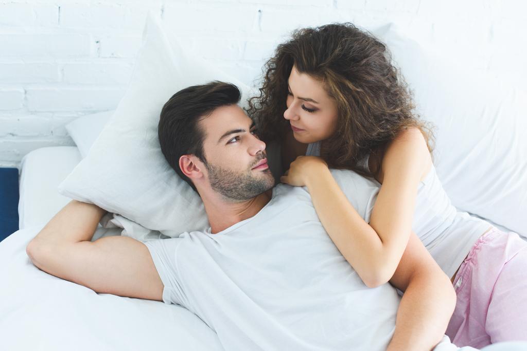 ベッドに横たわっている お互いを見て恋に美しい若いカップルのハイアングル ロイヤリティフリー写真 画像素材