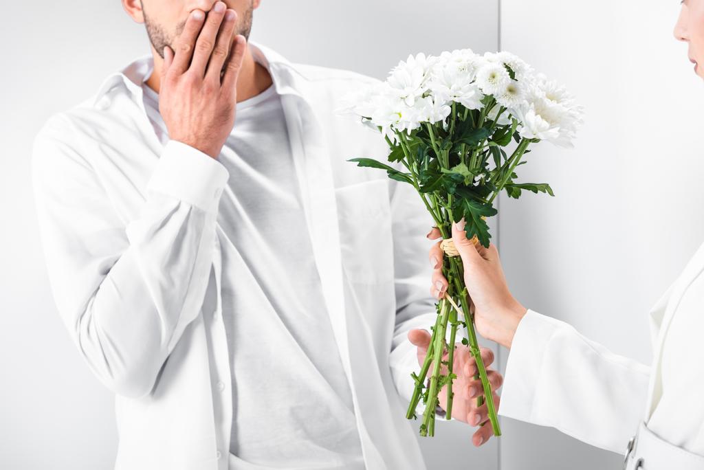 驚く男に花の花束を与えることの総白の女性のクローズ アップ ロイヤリティフリー写真 画像素材
