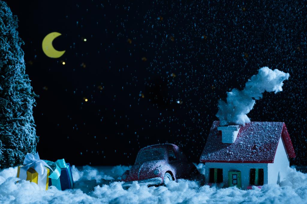クリスマス プレゼント 夜の雪で覆われたハウス おもちゃの車のクローズ アップ ショット ロイヤリティフリー写真 画像素材