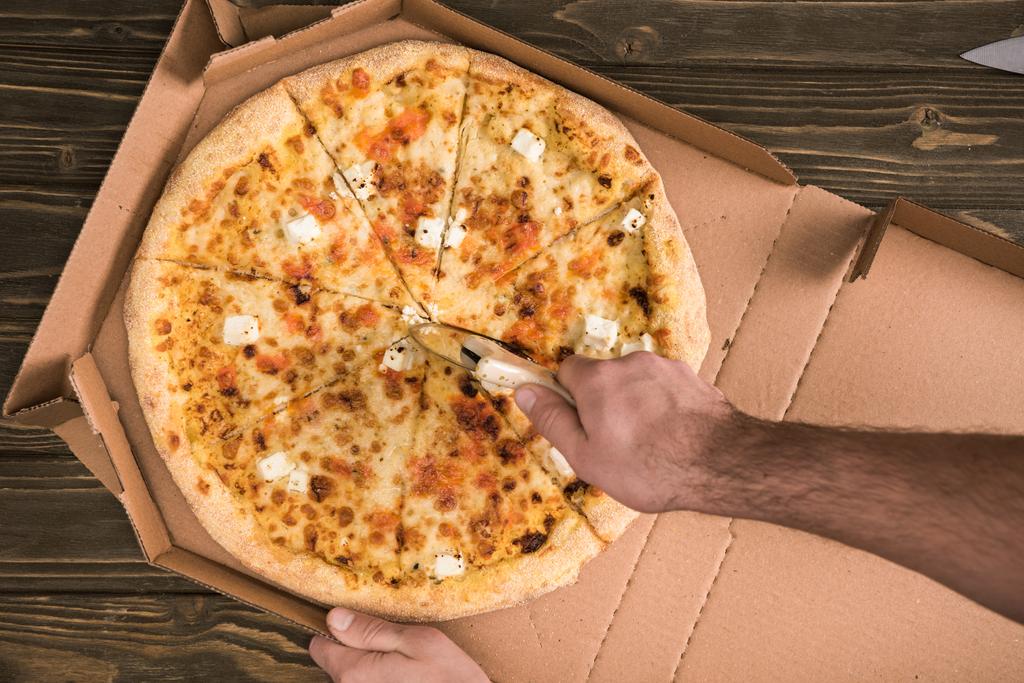 木製のテーブルにナイフで男カット チーズのピザの部分的なビュー ロイヤリティフリー写真 画像素材