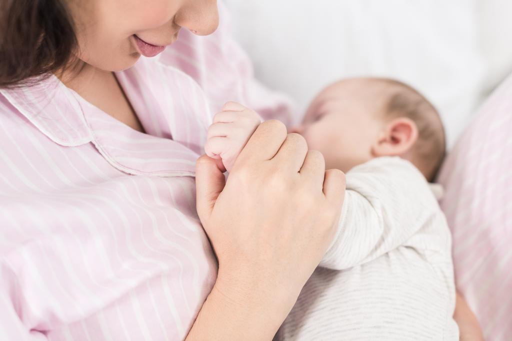 母親の手で眠っているかわいい赤ちゃんの部分的なビュー ロイヤリティフリー写真 画像素材