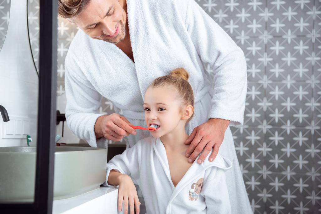 バスルームで歯を磨いて幸せな父を助ける娘 ロイヤリティフリー写真 画像素材