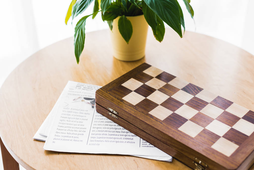 新聞とコーヒー テーブルの上の植物の近くに木のチェス ボード ロイヤリティフリー写真 画像素材