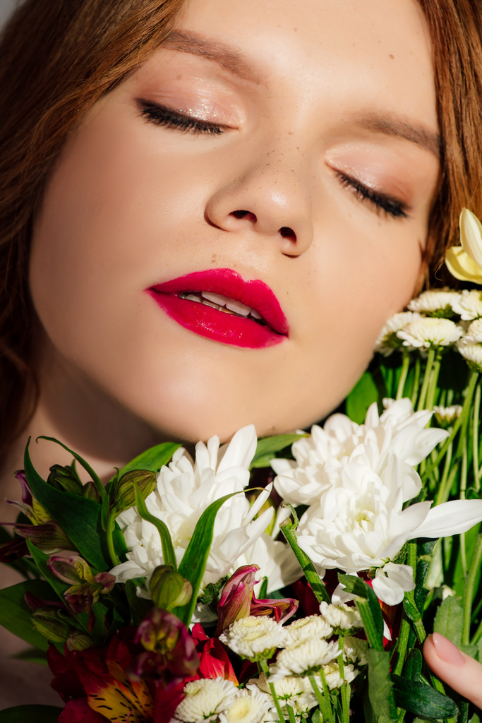 赤い唇を持つ美しい若い赤毛の女性のクローズアップと目が花でポーズを閉じた ロイヤリティフリー写真 画像素材