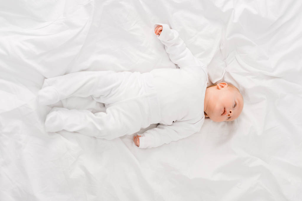 白いシートの上に横たわっている幼児の赤ちゃんのトップビュー ロイヤリティフリー写真 画像素材