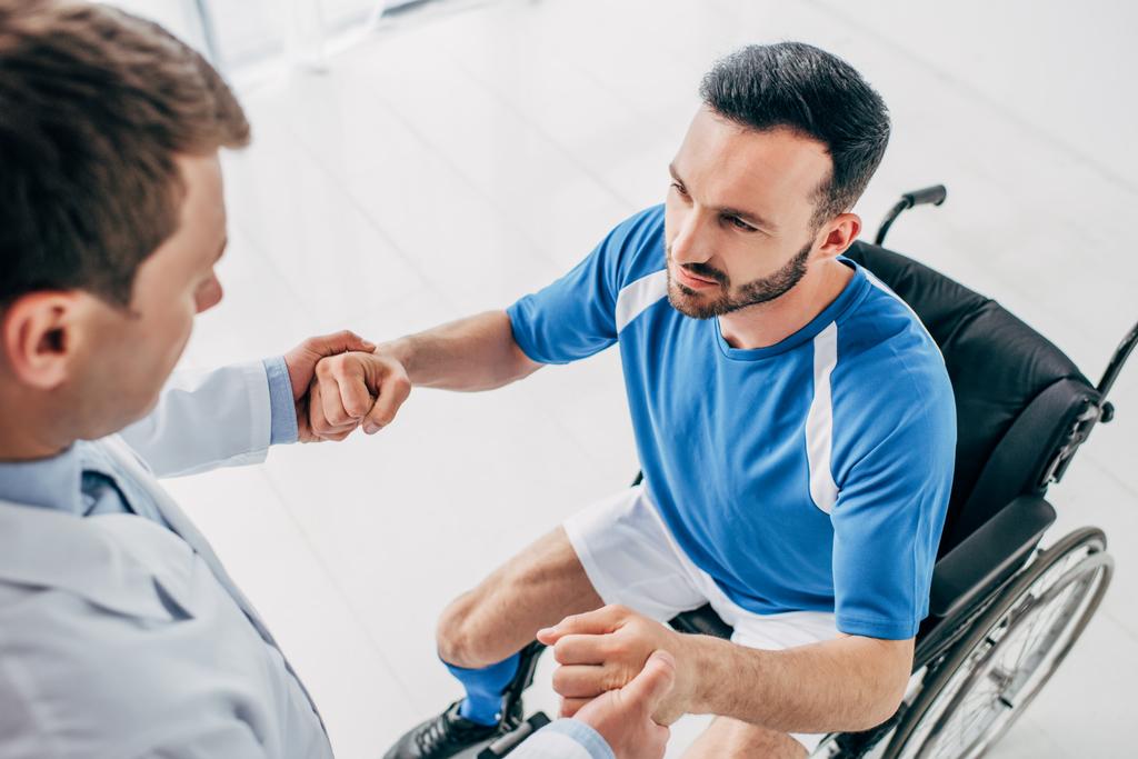 回復中に車椅子で障害のあるサッカー選手を助ける理学療法士 ロイヤリティフリー写真 画像素材