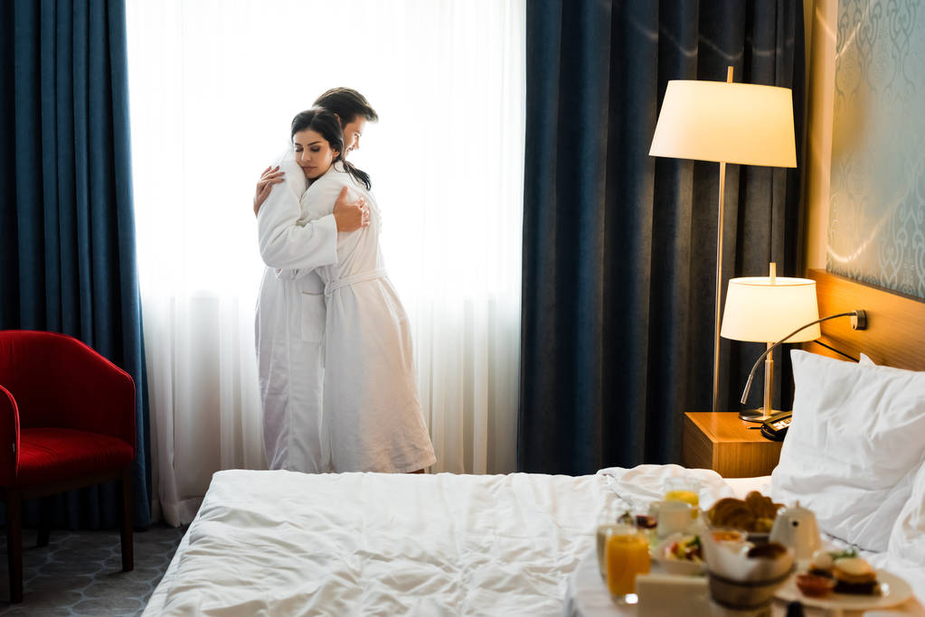 ホテルの部屋で抱きしめるハンサムな男と魅力的なブルネットの女性の選択的な焦点 ロイヤリティフリー写真 画像素材