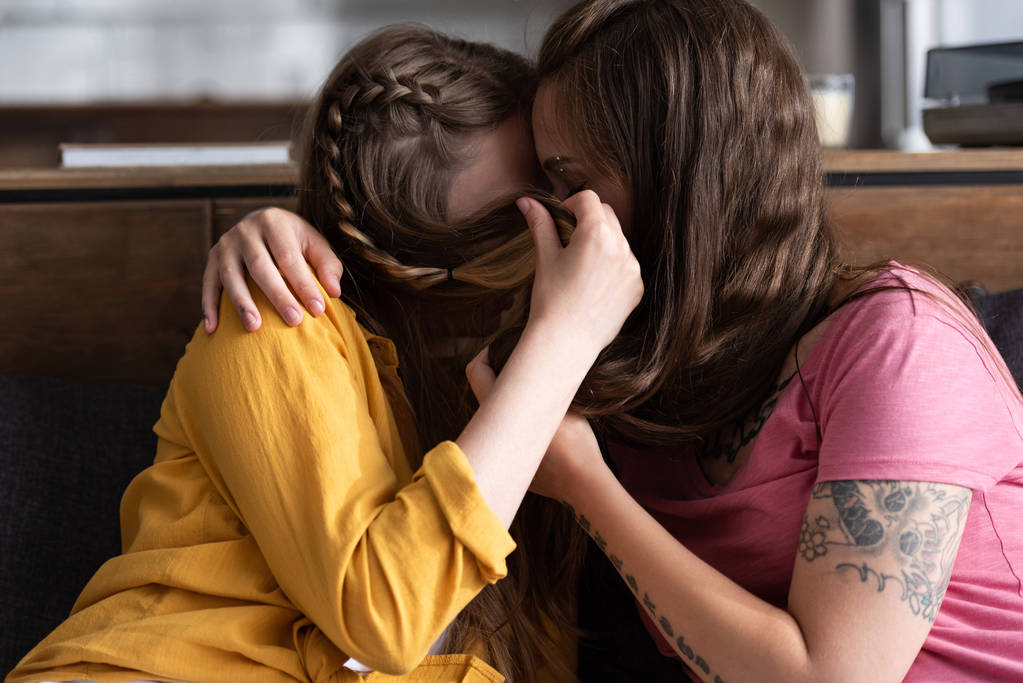 リビングルームで抱きしめてキスしながら 髪で顔を覆う2人のレズビアン ロイヤリティフリー写真 画像素材