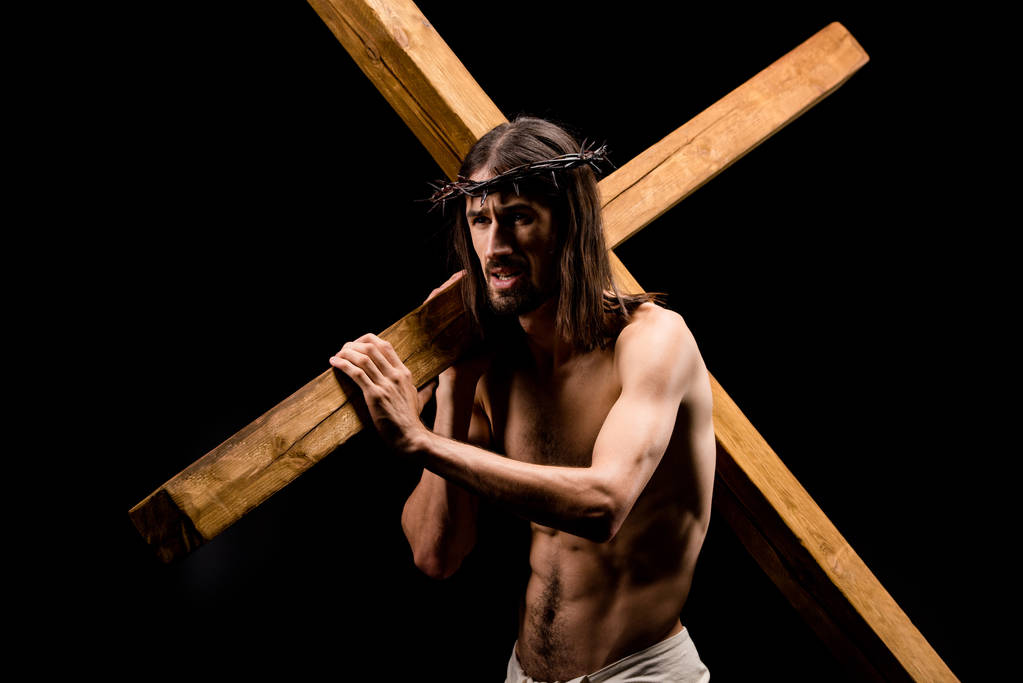 黒で隔離された重い木製の十字架を保持するスパイクを持つ花輪のイエス ロイヤリティフリー写真 画像素材