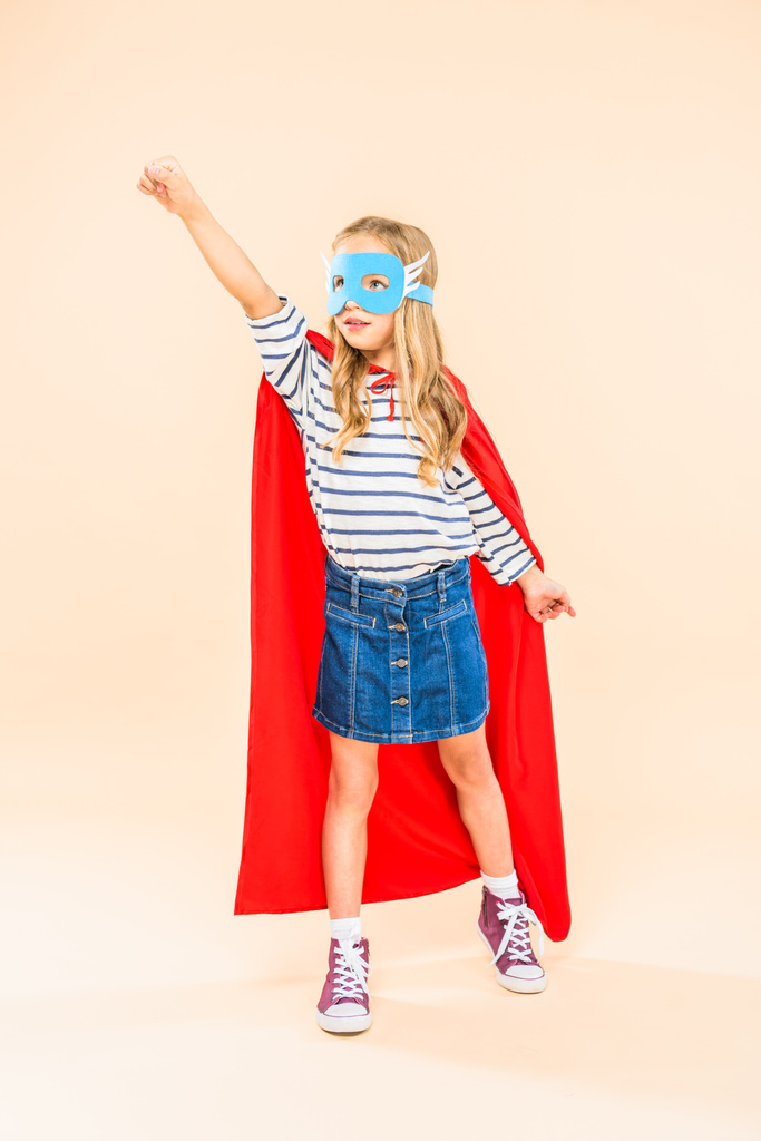 ピンクに拳を持ち上げるマスクとヒーローマントの子供の全長ビュー ロイヤリティフリー写真 画像素材