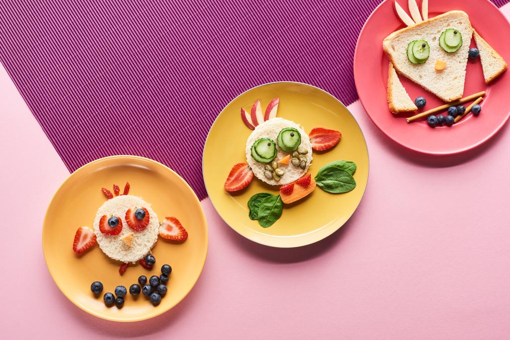 ピンクと紫の背景に食べ物で作られた派手な動物とプレートのトップビュー ロイヤリティフリー写真 画像素材