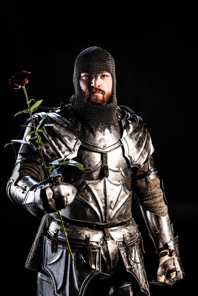 鎧を保持するハンサムな騎士は黒に隔離されたバラ ロイヤリティフリー写真 画像素材