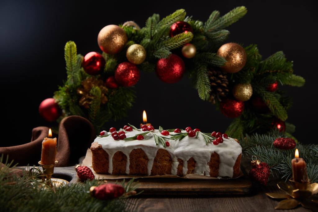 クリスマスリースの近くにクランベリーと伝統的なクリスマスケーキの選択的な焦点黒で隔離された木製のテーブルの上に赤ちゃんと ロイヤリティフリー写真 画像素材