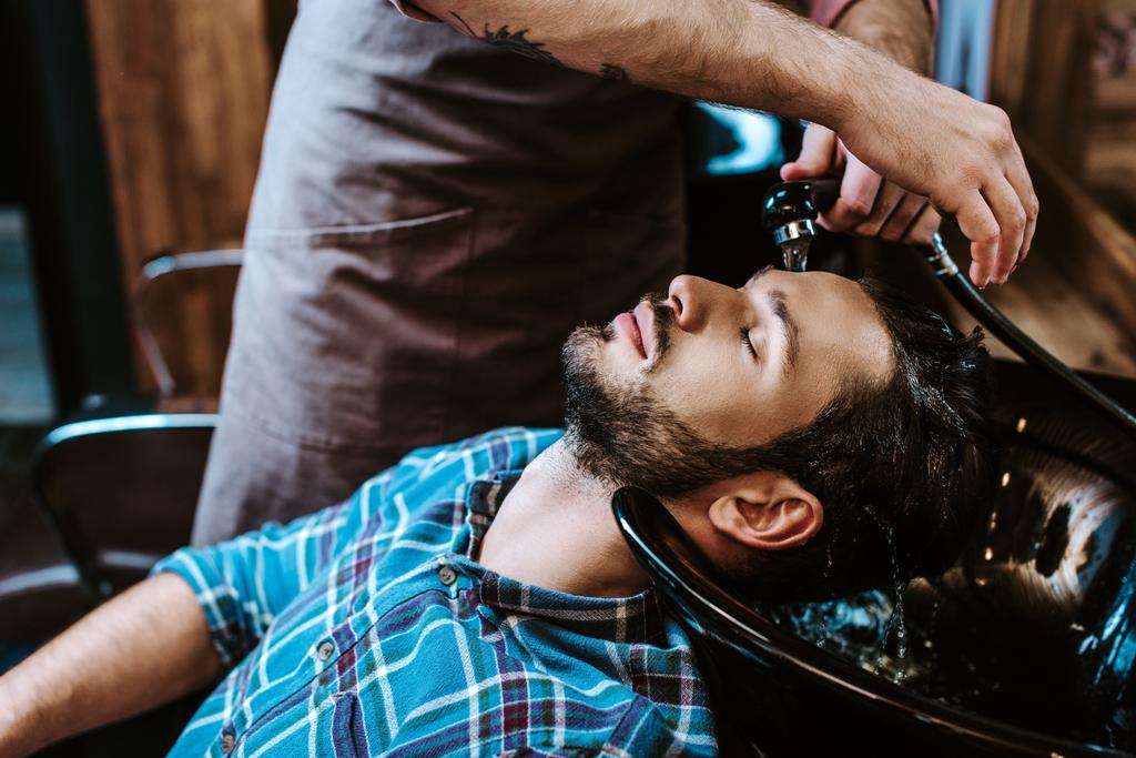 目を閉じた髭の男のタトゥーのある床屋の洗髪 ロイヤリティフリー写真 画像素材