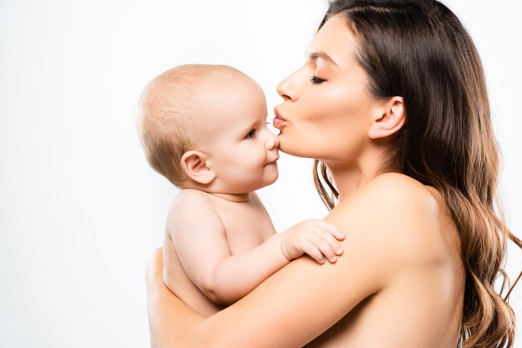 魅力的な裸の母親の肖像写真抱き合ってキスをする赤ちゃんの男の子 白に隔離された ロイヤリティフリー写真 画像素材