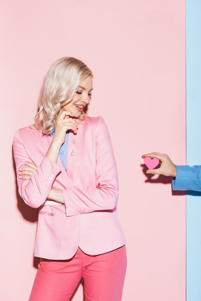ピンクと青の背景に笑顔の女性にハート型のカードを与える男のクロップドビュー ロイヤリティフリー写真 画像素材