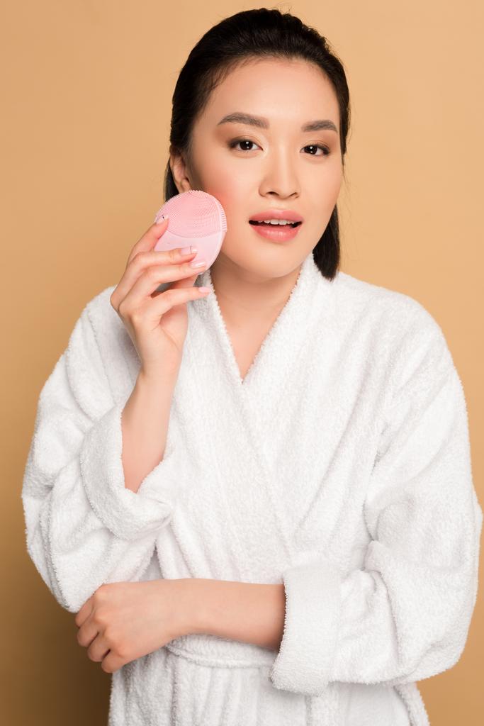 ベージュ地に洗顔ブラシで美人アジア人女性 ロイヤリティフリー写真 画像素材