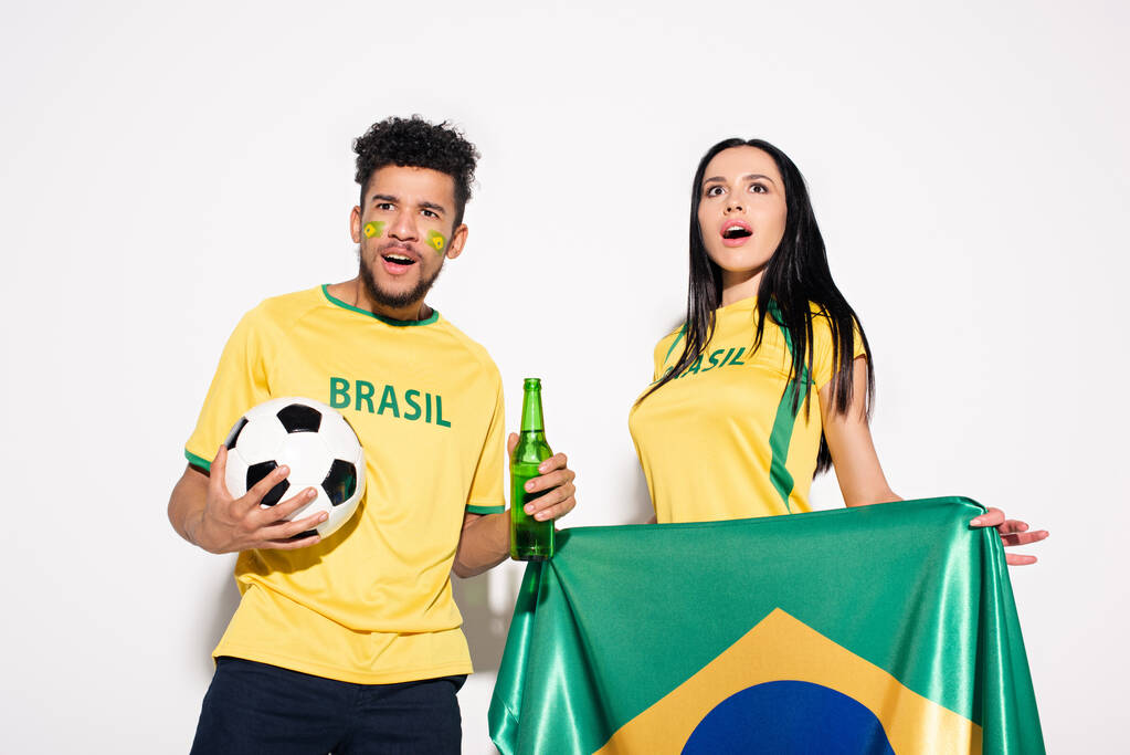 ブラジルの国旗とボールとビールを手にした驚くべきサッカーファンの多文化カップルが ロイヤリティフリー写真 画像素材