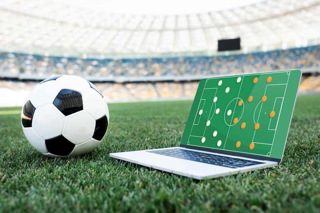 サッカーボールとラップトップでスタジアムの芝生のサッカーピッチに形成され ロイヤリティフリー写真 画像素材