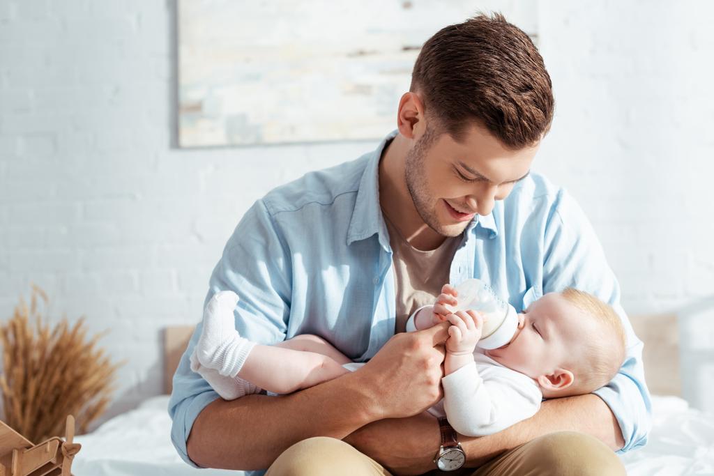 幸せな若い父親給餌かわいい赤ちゃん男の子とミルクから赤ちゃんボトル ロイヤリティフリー写真 画像素材