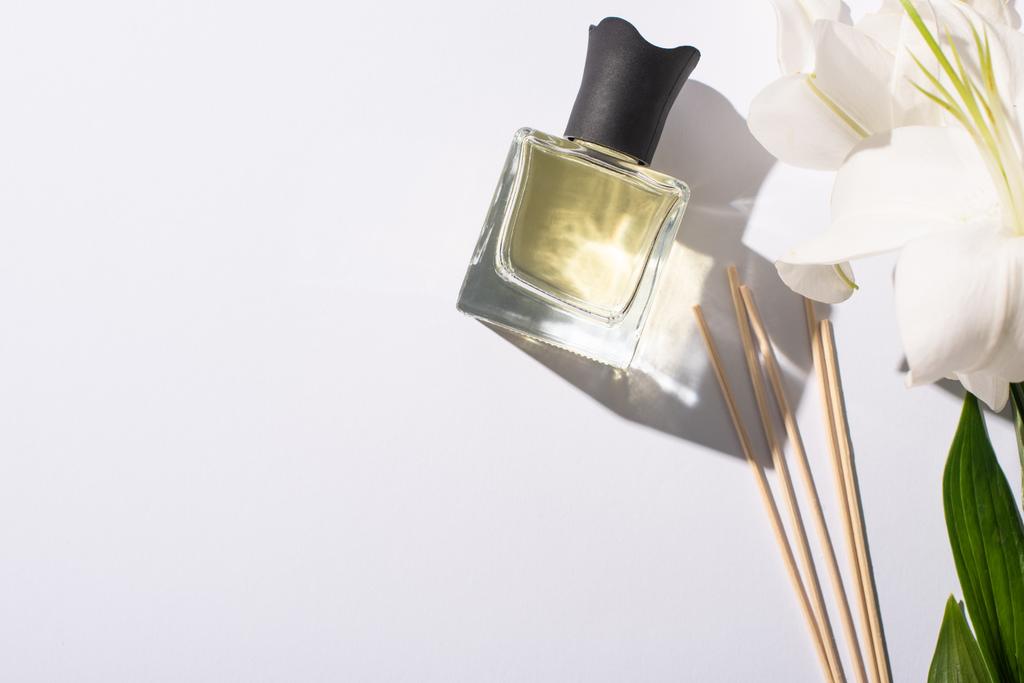 白い背景にユリの花の近くのボトルに香水のついた香りの棒のトップビュー ロイヤリティフリー写真 画像素材