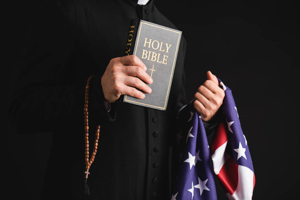 聖書やアメリカ国旗やバラ色のビーズを黒で隔てた聖職者の切り取りビュー ロイヤリティフリー写真 画像素材