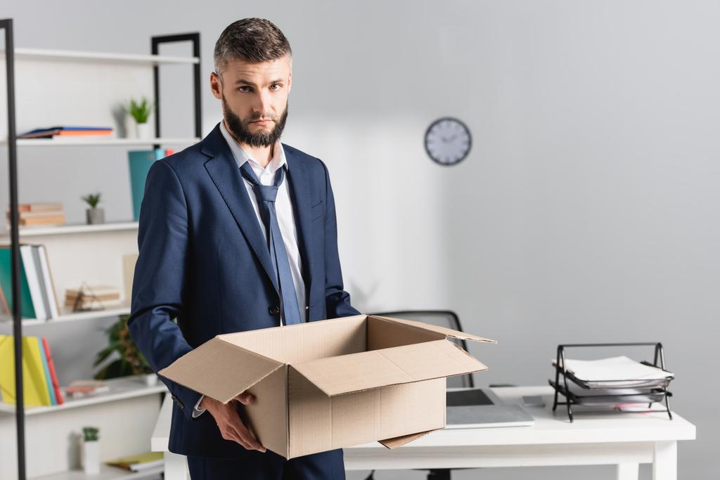 Fired Businessman Holding Cardboard Box With Office Table On Blurred Background Free Stock Photo And Image