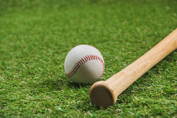 緑の草の上ボールを木製の野球バットのクローズ アップ ビュー ロイヤリティフリー写真 画像素材