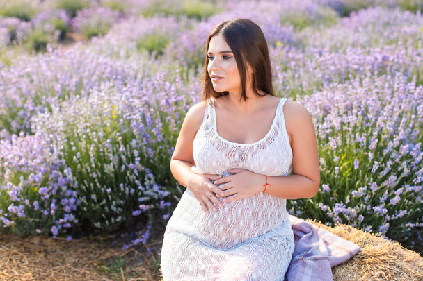 干し草ベール バイオレット ラベンダー畑の上に座っていると腹に触れて妊娠中の女性の笑顔 ロイヤリティフリー写真 画像素材