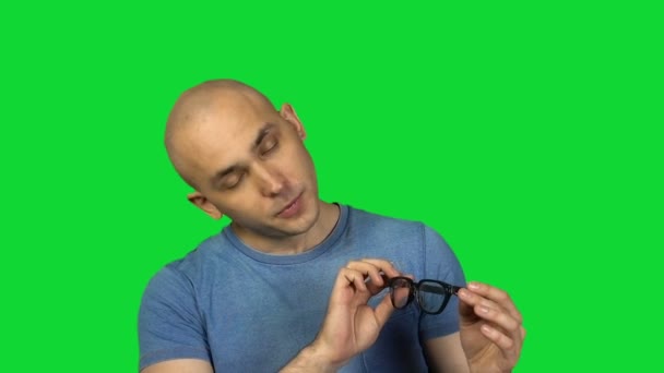 trägt Brille Mann mit Glatze auf grünem Hintergrund - Filmmaterial, Video.