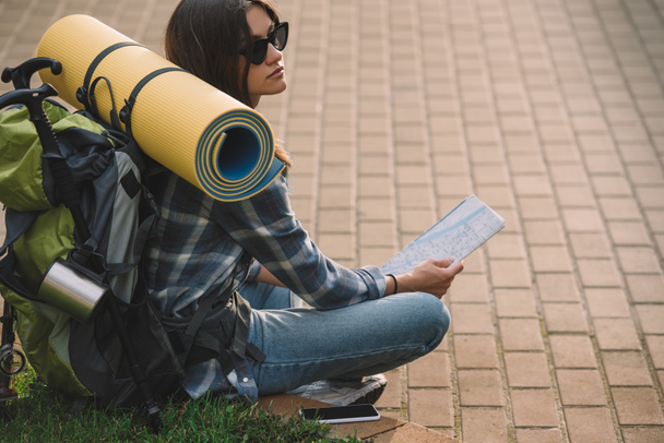 サングラス草の上に座って 地図を持って若い女性バックパッカー ロイヤリティフリー写真 画像素材