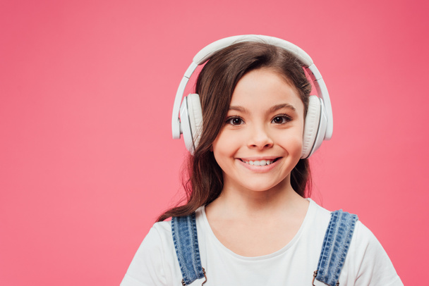 笑顔の子ピンクの分離のヘッドフォンで音楽を聴く ロイヤリティフリー写真 画像素材
