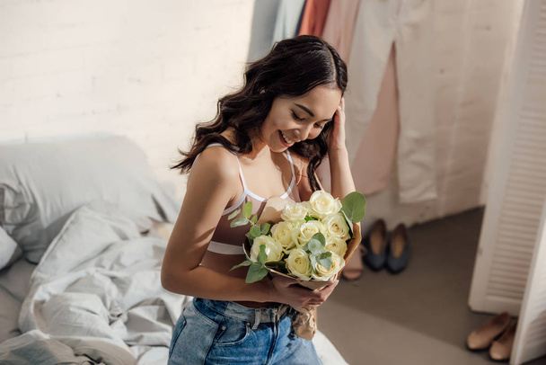 Beautiful happy young asian woman holding bouquet of white roses in bedroom  Free Stock Photo and Image