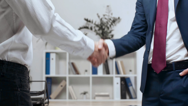 2 人のビジネスマンがオフィスで立ちながら握手の部分的なビュー ストック動画映像