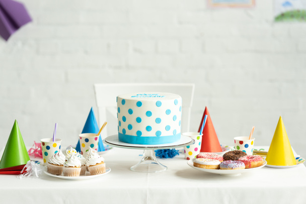 カップケーキ ドーナツ お祝いテーブルに紙コップで美味しい誕生日ケーキ ロイヤリティフリー写真 画像素材