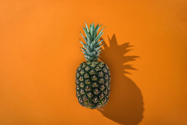 オレンジ色の背景にサイドシャドウを持つパイナップルのトップビュー ロイヤリティフリー写真 画像素材