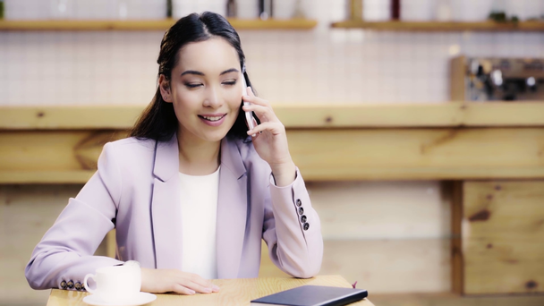 カフェでスマートフォンで話すスーツを着た笑顔とかわいいアジアの女性 ストック動画映像