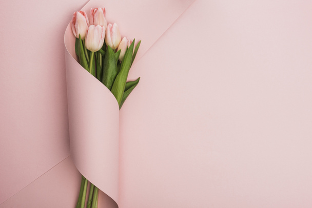ピンクの背景に紙の渦に包まれたチューリップの花束のトップビュー ロイヤリティフリー写真 画像素材