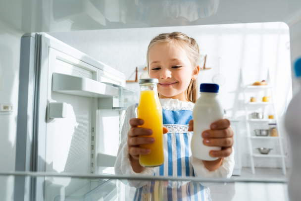 オレンジジュースと牛乳で瓶を持つ笑顔の子供の選択的な焦点 ロイヤリティフリー写真 画像素材