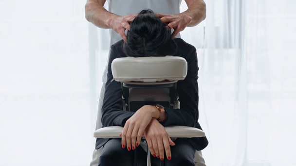 マッサージチェアでビジネスマンの女性に頭をマッサージするマッサージの部分的なビュー ストック動画映像