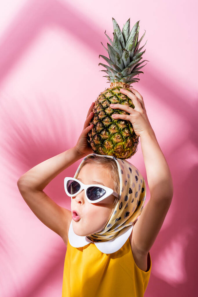 ピンクの上にパイナップルの頭を持つスカーフとサングラスでショックを受けた女の子 ロイヤリティフリー写真 画像素材